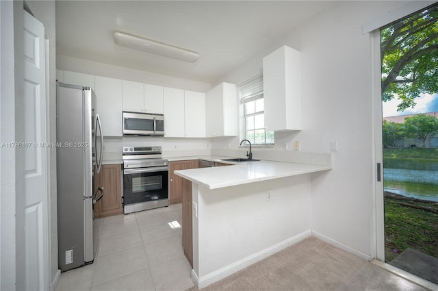 445 NE 21st Ave, Homestead, FL 33033 - kitchen with appliances with stainless steel finishes, a peninsula, light countertops, white cabinetry, and light tile patterned floors