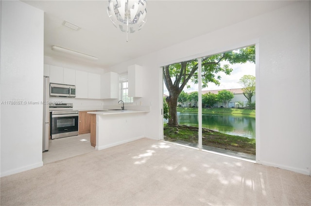 445 NE 21st Ave, Homestead, FL 33033 - kitchen with stainless steel appliances, light countertops, a water view, light carpet, and a peninsula