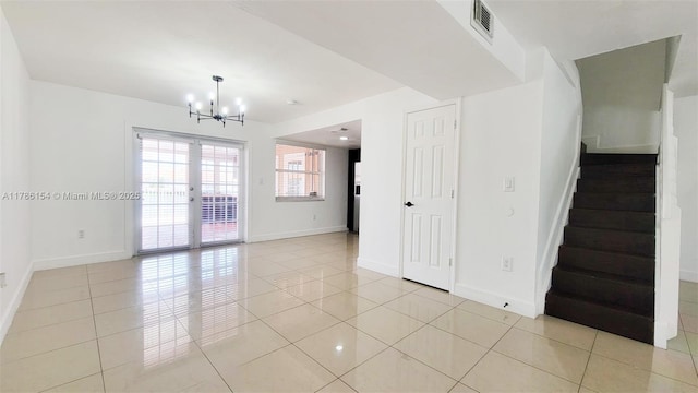 unfurnished room with visible vents, light tile patterned floors, baseboards, a chandelier, and stairs