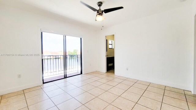 empty room featuring light tile patterned floors, baseboards, and ceiling fan