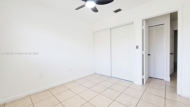 unfurnished bedroom featuring baseboards, visible vents, a ceiling fan, a closet, and light tile patterned floors