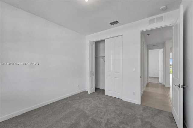 unfurnished bedroom featuring visible vents, carpet flooring, baseboards, and a closet