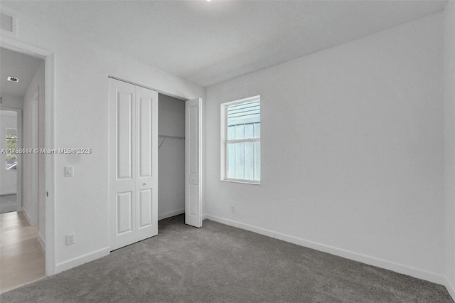 unfurnished bedroom with baseboards, carpet, and a closet