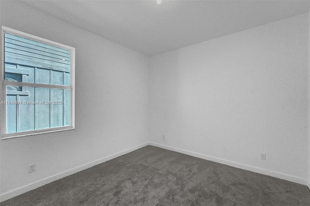 empty room with baseboards and dark carpet