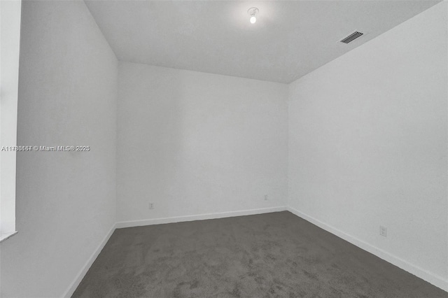 spare room featuring baseboards, dark colored carpet, and visible vents