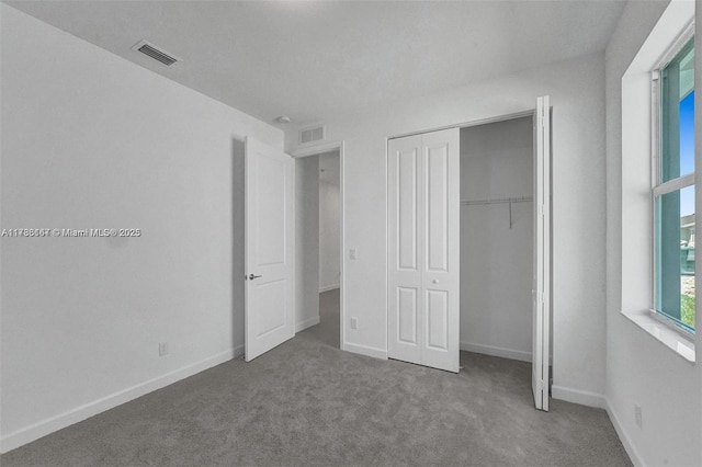 unfurnished bedroom featuring visible vents, carpet flooring, baseboards, and a closet