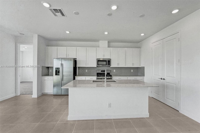 kitchen featuring white cabinets, a kitchen island with sink, stainless steel appliances, backsplash, and visible vents