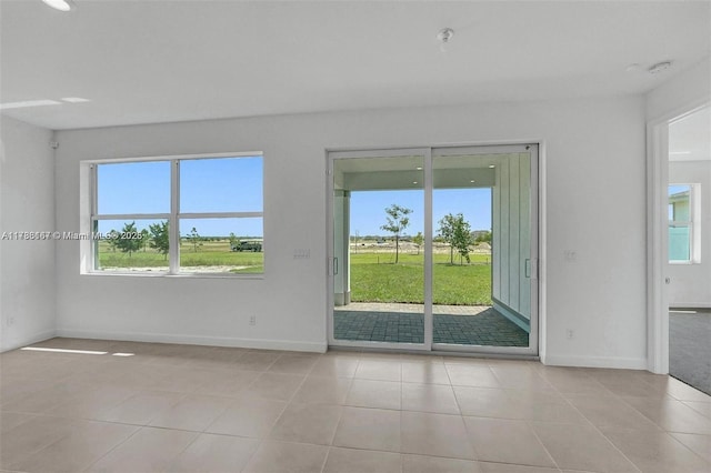 spare room featuring light tile patterned floors and baseboards