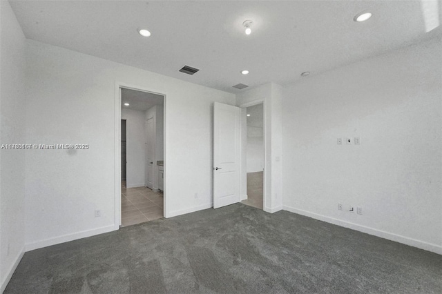 unfurnished bedroom featuring visible vents, dark colored carpet, baseboards, ensuite bathroom, and recessed lighting