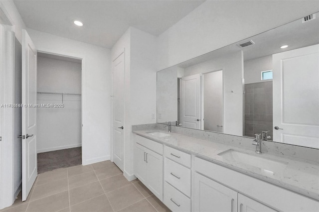 bathroom featuring a sink, tile patterned floors, double vanity, and a walk in closet