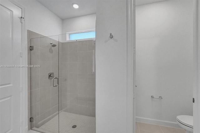 bathroom featuring toilet, baseboards, tile patterned flooring, and a stall shower