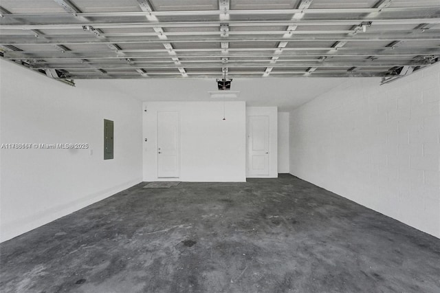 garage featuring concrete block wall, a garage door opener, and electric panel