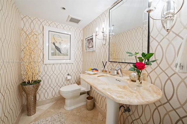 bathroom with wallpapered walls, toilet, visible vents, a sink, and tile patterned flooring