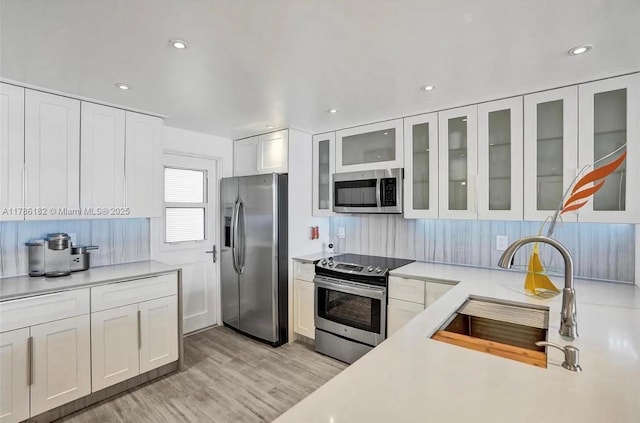 2200 NE 33rd Ave Unit 10F, Fort Lauderdale, FL 33305 - kitchen with a sink, decorative backsplash, light wood-style floors, stainless steel appliances, and light countertops