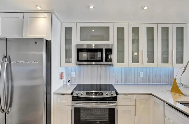 2200 NE 33rd Ave Unit 10F, Fort Lauderdale, FL 33305 - kitchen featuring white cabinets, glass insert cabinets, light countertops, and appliances with stainless steel finishes