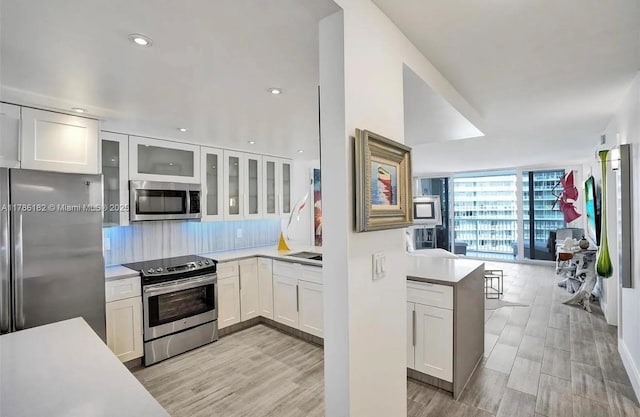 2200 NE 33rd Ave Unit 10F, Fort Lauderdale, FL 33305 - kitchen with tasteful backsplash, glass insert cabinets, stainless steel appliances, light countertops, and white cabinetry