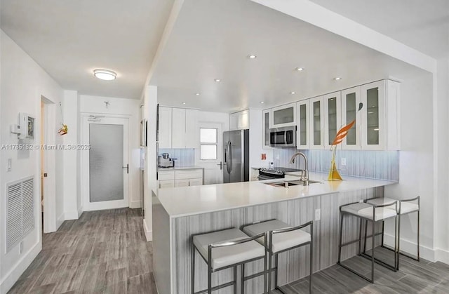 2200 NE 33rd Ave Unit 10F, Fort Lauderdale, FL 33305 - kitchen with stainless steel appliances, wood finished floors, a sink, a peninsula, and a breakfast bar area