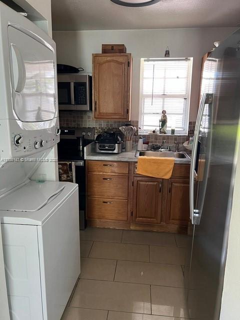 12045 SW 18th St Unit 1-42, Miami, FL 33175 - kitchen featuring stainless steel appliances, stacked washer / dryer, light countertops, and backsplash