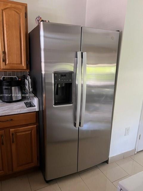 12045 SW 18th St Unit 1-42, Miami, FL 33175 - kitchen featuring stainless steel fridge with ice dispenser, brown cabinets, light tile patterned floors, light countertops, and tasteful backsplash
