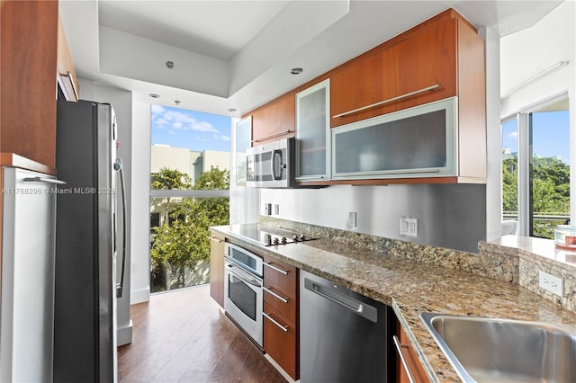 110 Washington Ave Unit 2307, Miami Beach, FL 33139 - kitchen with stainless steel appliances, glass insert cabinets, dark wood-style floors, light stone counters, and brown cabinetry