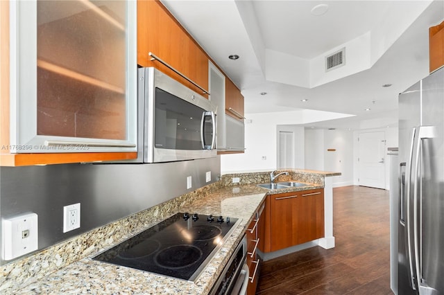 110 Washington Ave Unit 2307, Miami Beach, FL 33139 - kitchen featuring stainless steel appliances, brown cabinets, a peninsula, dark wood finished floors, and light stone counters