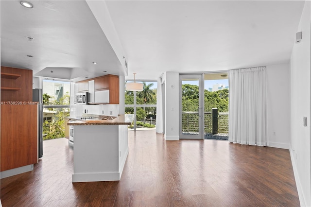 110 Washington Ave Unit 2307, Miami Beach, FL 33139 - kitchen with appliances with stainless steel finishes, floor to ceiling windows, dark wood-type flooring, dark countertops, and brown cabinets