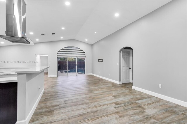8612 SW 159th Pl, Miami, FL 33193 - unfurnished living room featuring arched walkways, lofted ceiling, recessed lighting, and light wood-style flooring