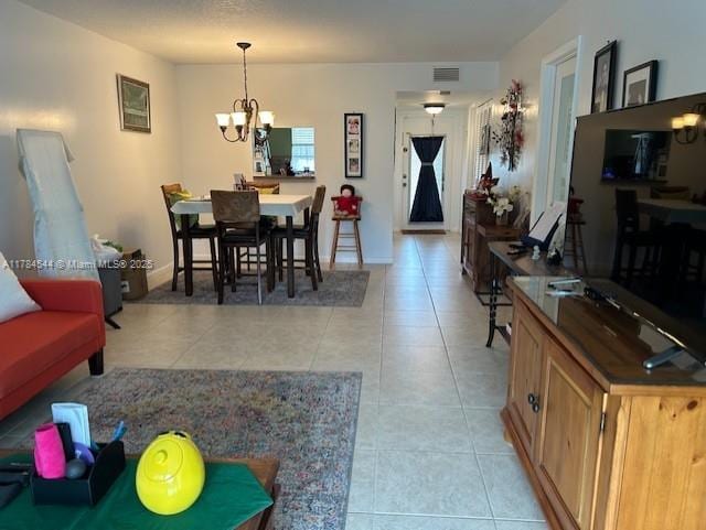 living area with a chandelier, visible vents, baseboards, and light tile patterned flooring