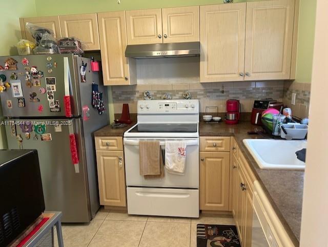 kitchen with under cabinet range hood, dishwasher, a sink, freestanding refrigerator, and electric range