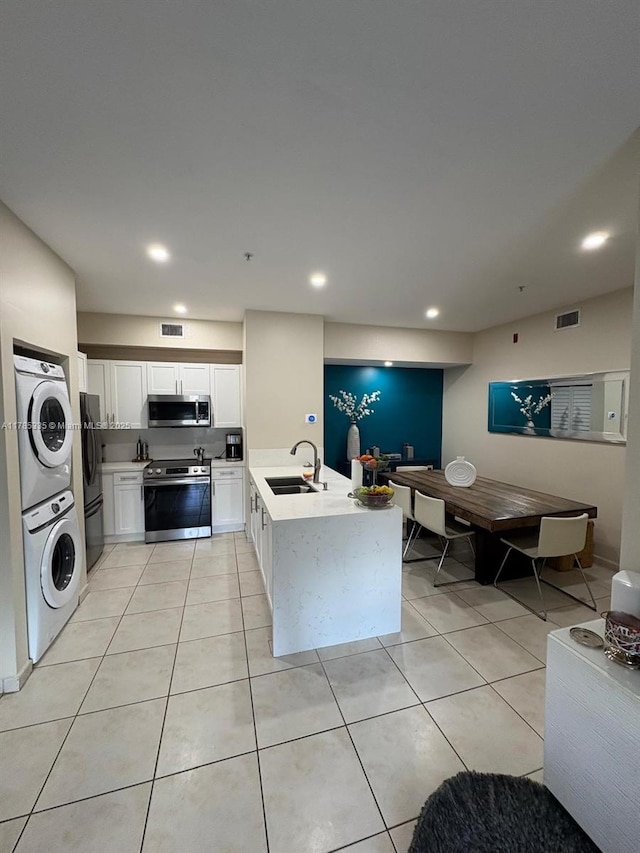 7340 NW 114th Ave Unit 201, Doral, FL 33178 - kitchen featuring stainless steel appliances, stacked washer and clothes dryer, a sink, a peninsula, and white cabinets