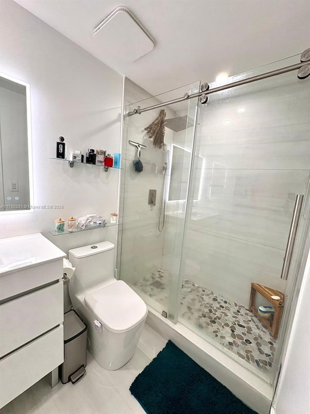 bathroom with a shower stall, toilet, vanity, and tile patterned floors