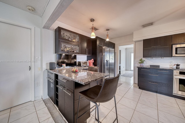7215 SW 16th St, Miami, FL 33155 - kitchen with a breakfast bar area, appliances with stainless steel finishes, visible vents, stone countertops, and marble finish floor