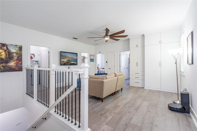 living area with light wood-style floors, visible vents, and ceiling fan