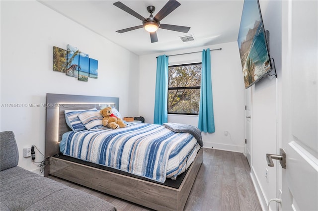 bedroom featuring baseboards, ceiling fan, visible vents, and wood finished floors