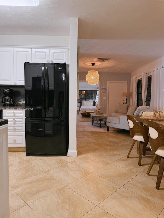 kitchen with freestanding refrigerator, white cabinetry, open floor plan, and dark countertops