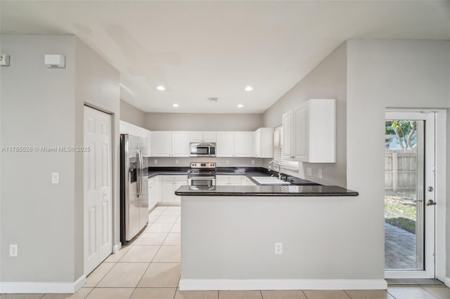146 NE 36th Ter, Homestead, FL 33033 - kitchen with dark countertops, a sink, stainless steel appliances, a peninsula, and white cabinetry