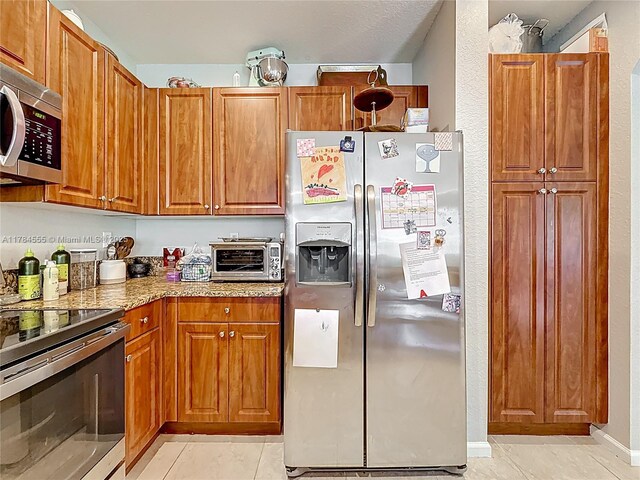 294 Las Brisas Cir, Sunrise, FL 33326 - kitchen with stainless steel appliances, brown cabinetry, and light tile patterned floors