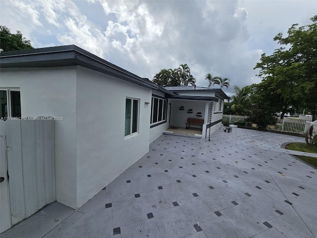 12585 NE Miami Ct, North Miami, FL 33161 - view of property exterior with fence, stucco siding, and a patio area