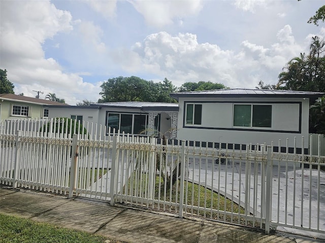 12585 NE Miami Ct, North Miami, FL 33161 - view of front facade featuring a standing seam roof, stucco siding, a fenced front yard, and metal roof