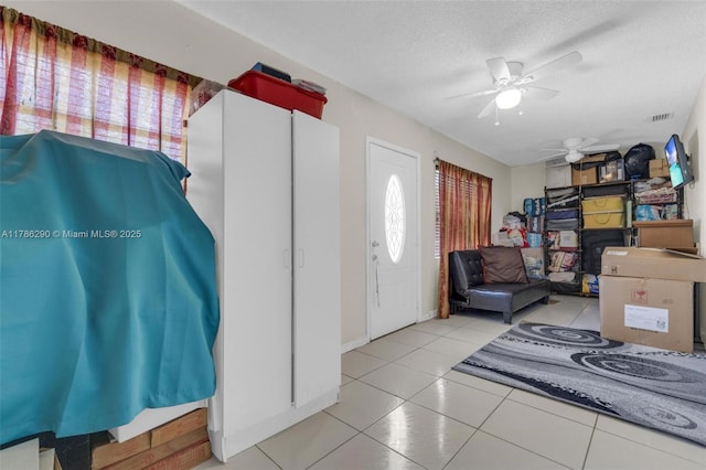 tiled foyer entrance with a textured ceiling, visible vents, ceiling fan, and a healthy amount of sunlight