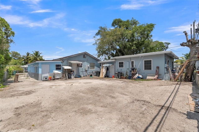 rear view of property featuring fence, central air condition unit, and stucco siding