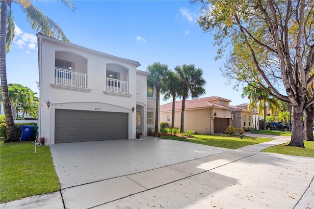 mediterranean / spanish-style house featuring an attached garage, driveway, stucco siding, and a balcony