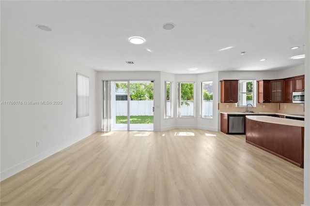 kitchen with baseboards, open floor plan, light wood-type flooring, light countertops, and stainless steel appliances