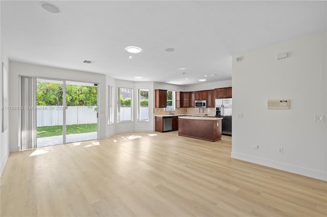 unfurnished living room featuring baseboards, a wealth of natural light, and light wood-style flooring
