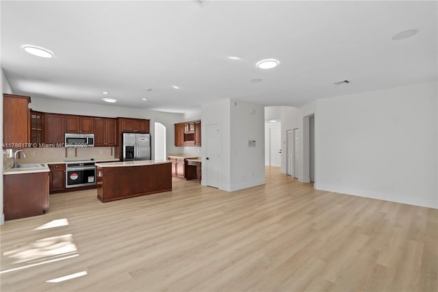 kitchen featuring a sink, light countertops, stainless steel appliances, light wood-type flooring, and a kitchen island