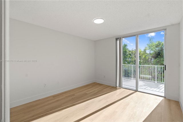 spare room with baseboards and wood finished floors