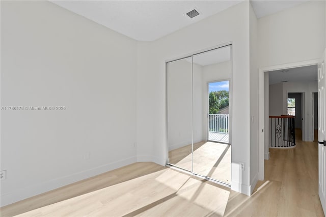 empty room featuring baseboards, wood finished floors, and visible vents