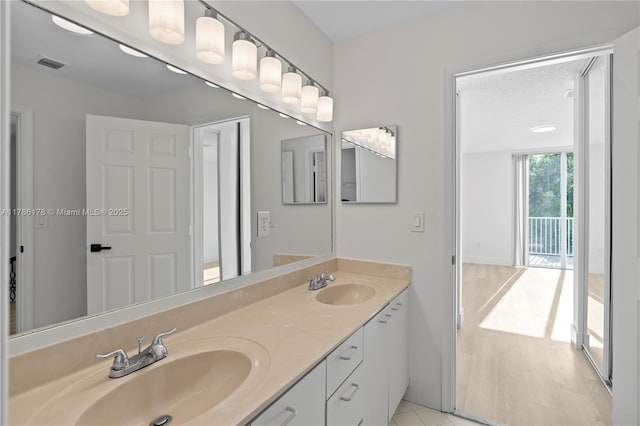 full bathroom featuring double vanity, visible vents, a sink, and wood finished floors