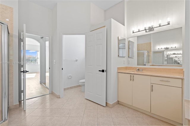 bathroom with a towering ceiling, tile patterned flooring, a stall shower, vanity, and toilet