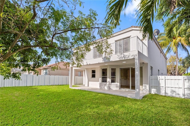 rear view of house with a fenced backyard, a patio, stucco siding, and a balcony